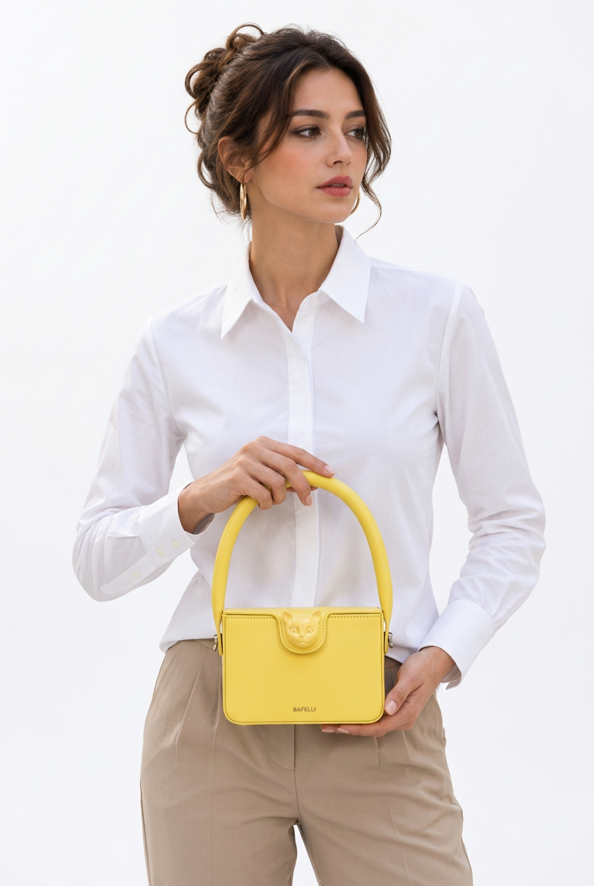 Stéphanie présentant le petit sac BAFELLI jaune en cuir de vachette avec fermoir tête de chat